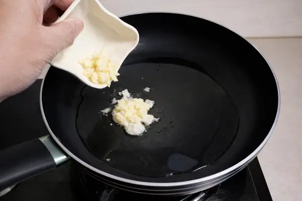 Adding ginger garlic paste to hot oil in a pan for mince