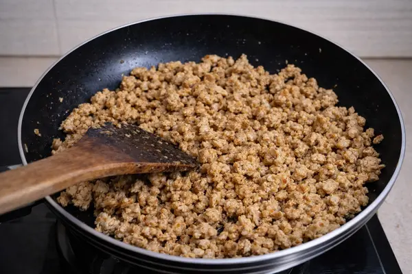 Cooked chicken mince ready for pizza topping after moisture dries