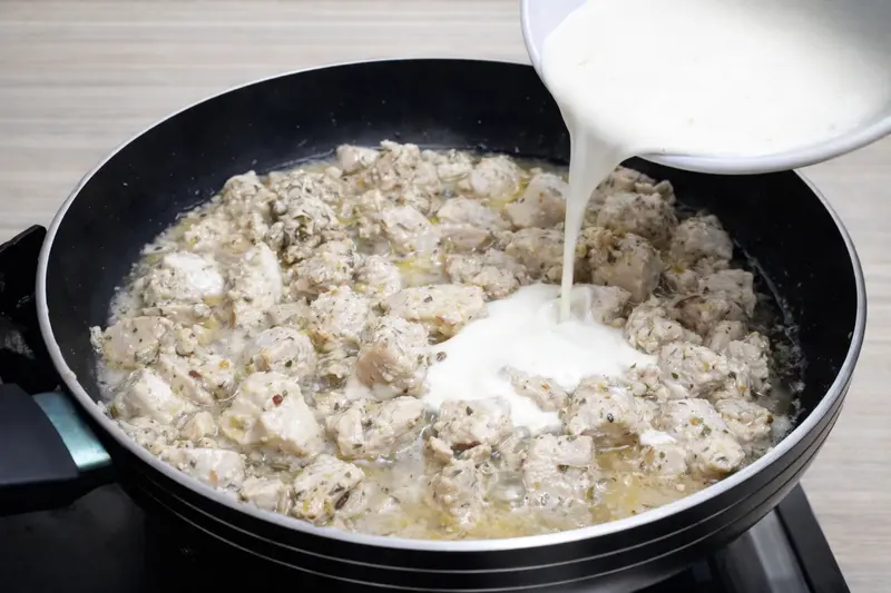 Chicken cooking in pan with cream added after releasing moisture