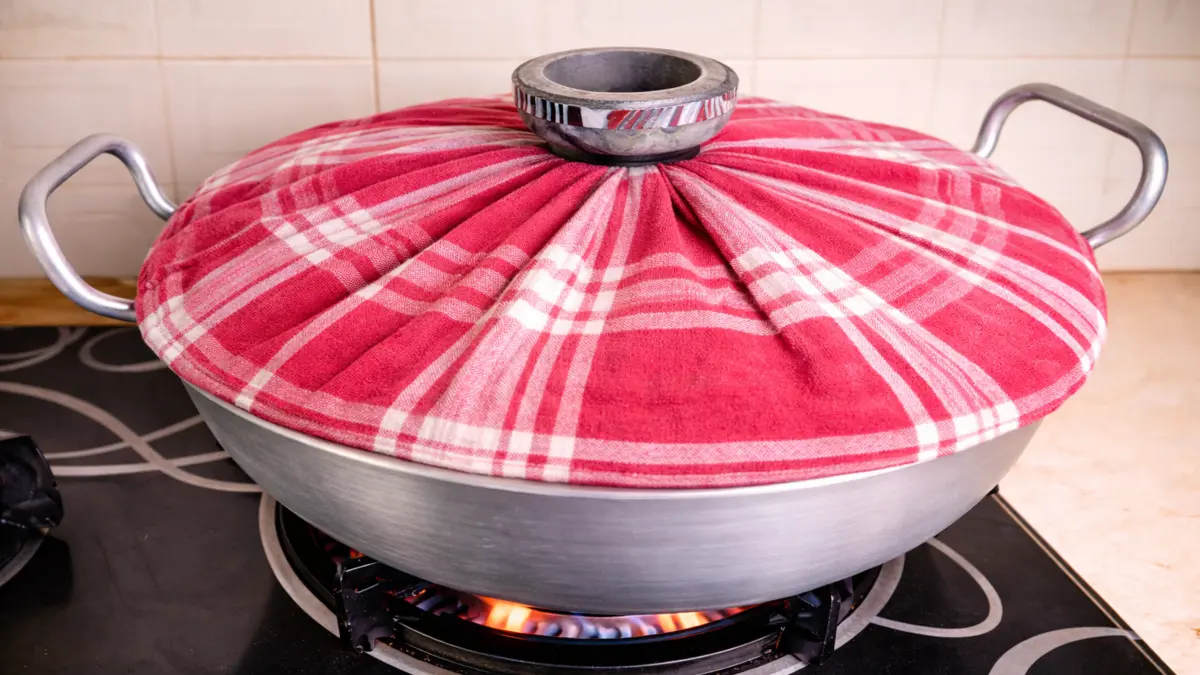 wok lid fully covered with cotton cloth to control steam during cake baking