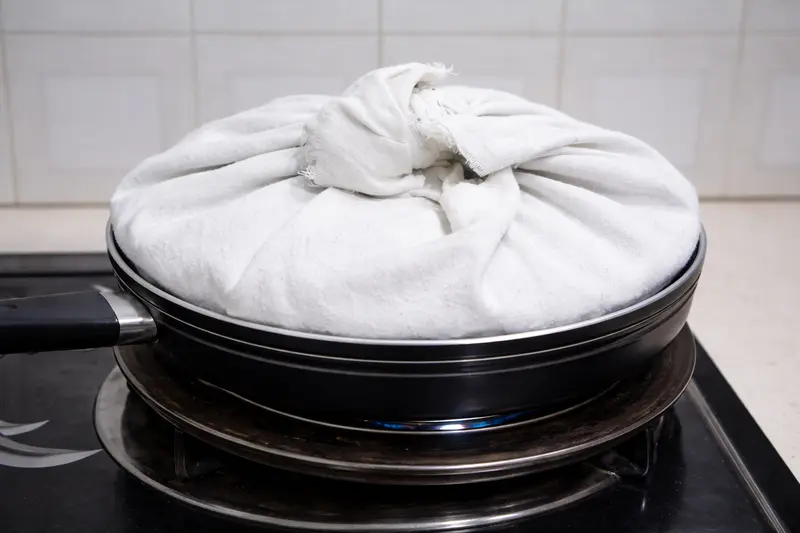 Pan covered with lid wrapped in thick cotton cloth for steam control