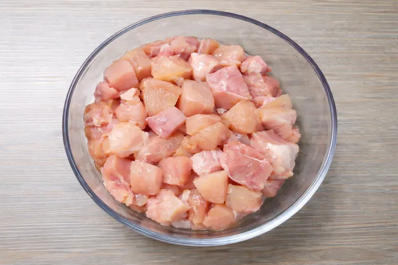 Boneless chicken breast cut into medium-sized cubes in a glass bowl for creamy chicken
