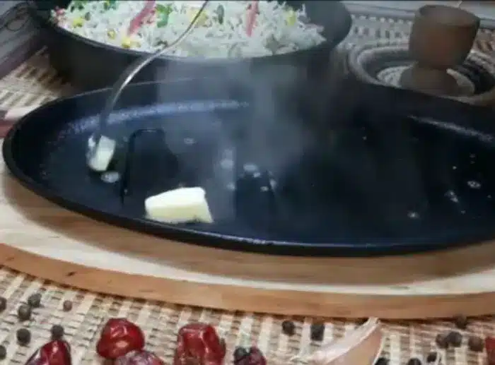 lubricating the hot sizzling plate with butter
