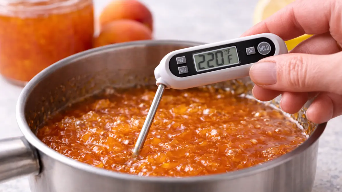 Jam Temperature Test (220°F / 104°C) Hand holding a thermometer in jam showing the setting temperature