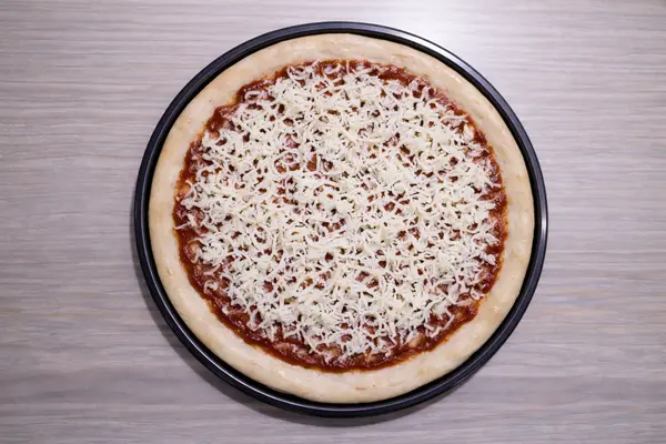 Light layer of shredded cheese spread over pizza sauce