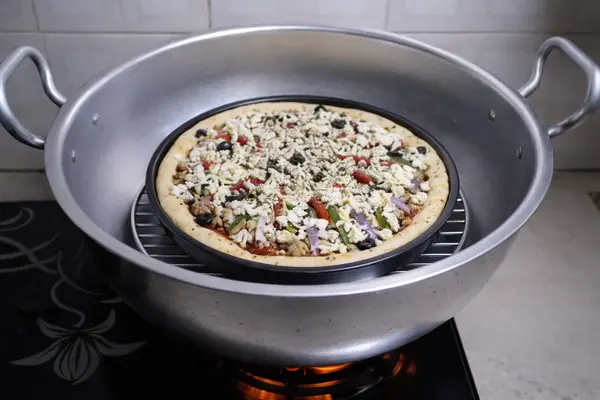Pizza placed inside preheated wok over metal spacer for baking
