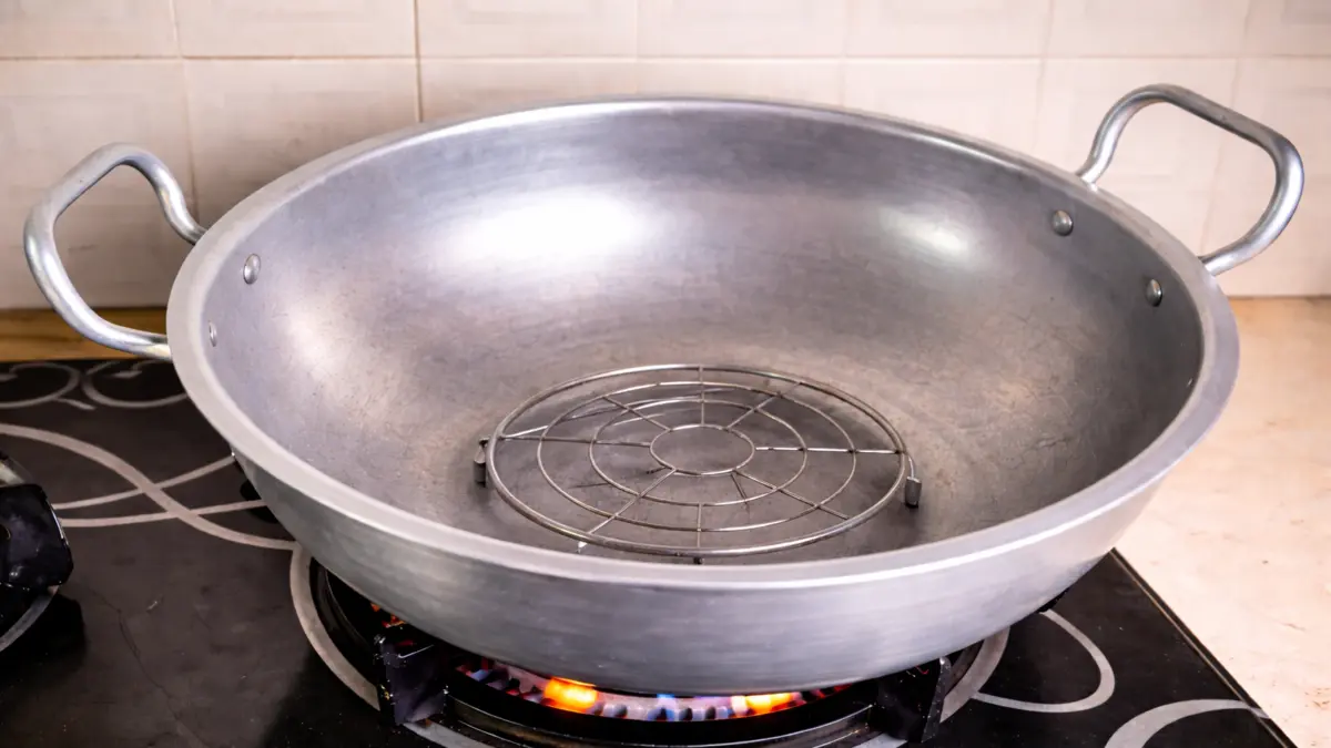placing a metal stand inside a wok to prevent cake from burning