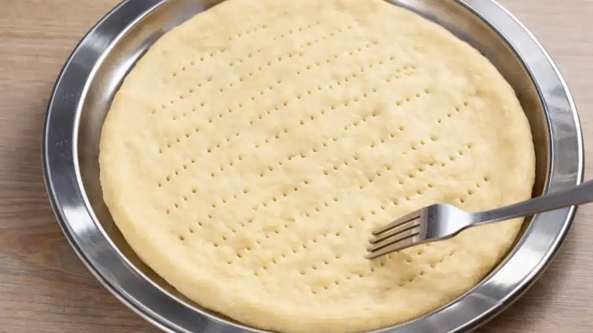 Pricking pizza dough with a fork to prevent air bubbles while baking