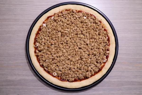 Cooked chicken mince evenly spread over pizza base