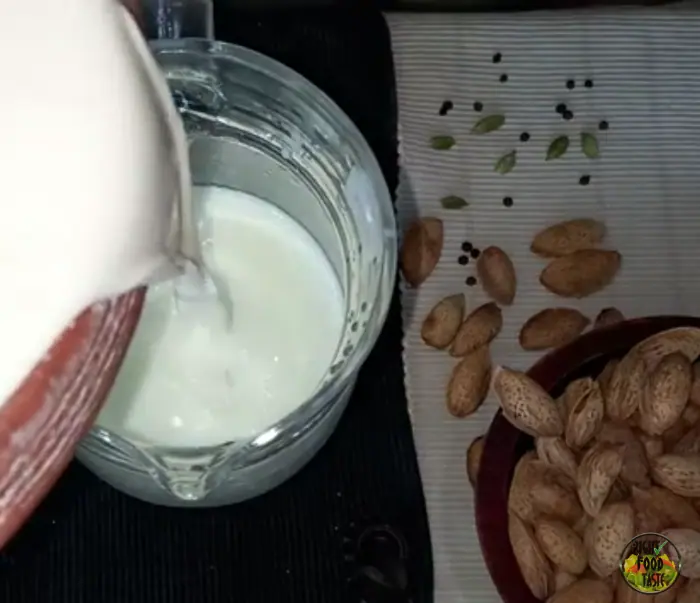 pouring the blended thandai mixture into the sweetened milk