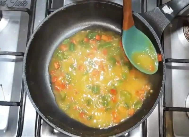 Cornflour slurry added to thicken orange vegetable sauce smoothly